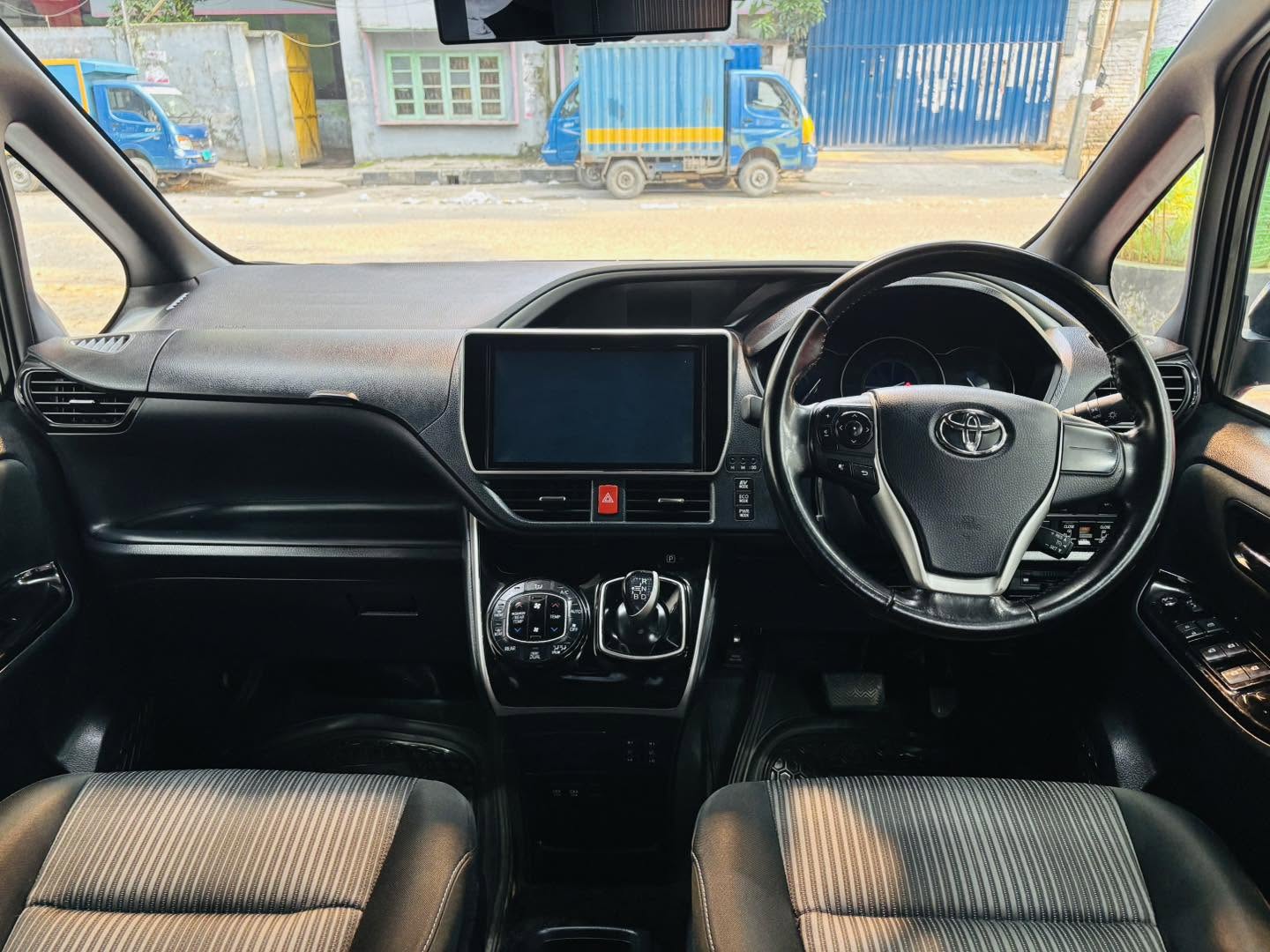 Hybrid used cars for sale in Dhaka featuring a clean Toyota Noah dashboard, steering wheel and front cabin